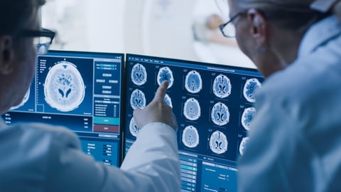 In Control Room Doctor and Radiologist Discuss Diagnosis while Watching Procedure and Monitors Showing Brain Scans Results, In the Background Patient Undergoes MRI or CT Scan Procedure.; Shutterstock ID 1243951690