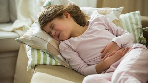 Child lying on sofa in the living room with stomach pain. Hands on belly. Little girl suffering; Shutterstock ID 1294511005