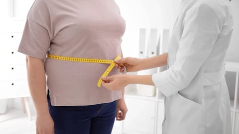 Doctor measuring waist of overweight woman in clinic, closeup; Shutterstock ID 1423277024
