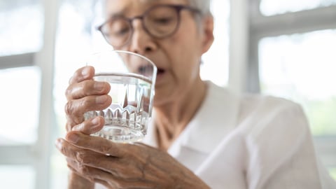 Senior woman holding glass of water,hand shaking while drinking water,elderly patient with hands tremor uncontrolled body tremors,symptom of essential tremor,parkinson's disease,neurological disorders; Shutterstock ID 1685125852