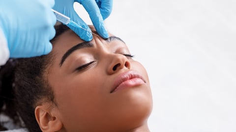Plastic surgery. Young african woman receiving botox injection in interbrow zone at beauty clinic, closeup, copy space; Shutterstock ID 1753026176