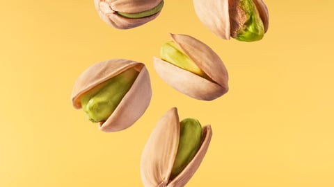 Flying in air fresh raw whole and cracked pistachios  isolated on yellow background. High resolution image; Shutterstock ID 1784812778