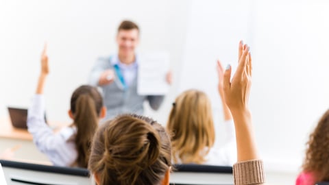 image of a female hand raised in university classroom; Shutterstock ID 183370955