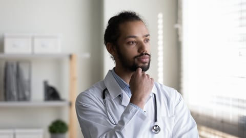 Head shot of pensive young African American man doctor looking in distance, touching chin, thoughtful serious physician general practitioner surgeon in white uniform thinking and visualizing; Shutterstock ID 2078659729