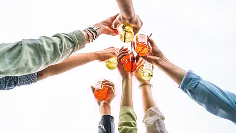 Best friends raising cocktail glasses celebrating a toast - closeup on the hands - arms up against a white sky background - people using alcohol and alcoholic drinks concept; Shutterstock ID 2161015131