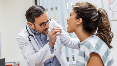 Doctor using inspection spatula to examine patient throat. ENT doctor doing throat exam of a woman. patient opened her mouth to throat check-up; Shutterstock ID 2168008549