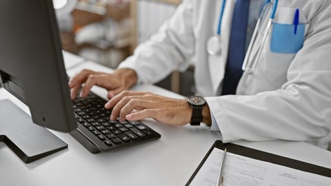 Young hispanic man doctor using computer working at the clinic; Shutterstock ID 2349503911