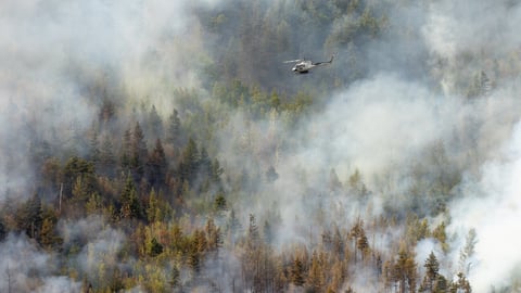 Rescue helicopter flying over a mountainside forest fire near Sparwood, British Columbia, Canada during the 2023 wildfire season; Shutterstock ID 2400912575