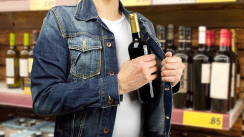 man in a supermarket stealing a bottle of champagne; Shutterstock ID 246155941