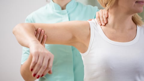 Physical therapist diagnosing patient with painful arm; Shutterstock ID 260864429