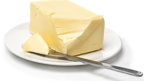 Piece of butter on white plate with knife. White background and shallow focus.; Shutterstock ID 46939705