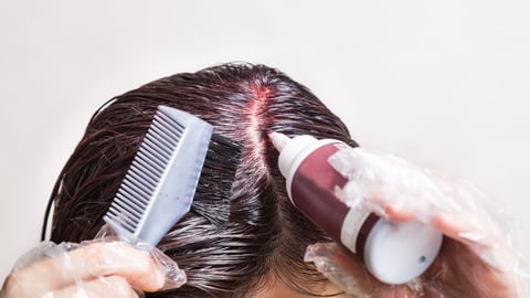 Woman attempting to apply chemical hair color onto scalp.  Self help solution.; Shutterstock ID 762186148