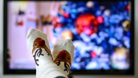 Person's feed in Christmas socks in front of the TV