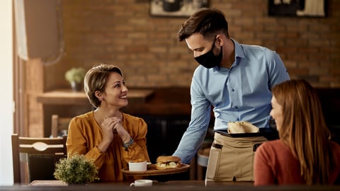 waiter in COVID mask serving patrons