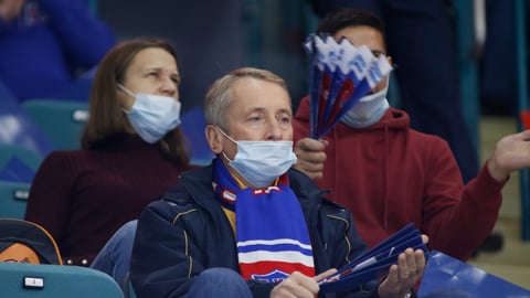 Man watching sports with COVID mask down halfway