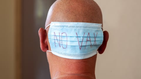 Man with backward mask that says "No Vax"