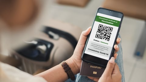 Woman holding vaccine passport with QR code on cellphone