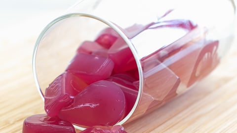 Purple jellies spill out of a water glass
