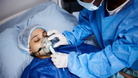 doctor or nurse taking care of young women in bed with ventilator