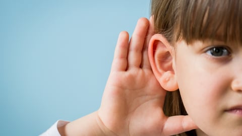 Young girl holding her hand behind her ear to hear better