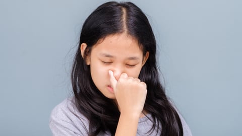 child holding nose as if in pain