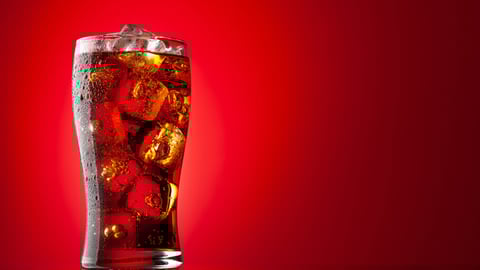 cola in glass with ice red background.