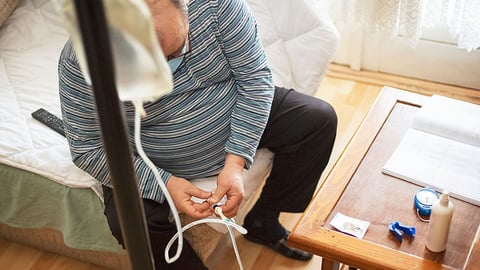 a senior man sits on a bed and receives intravenous medication