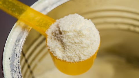 Close up of yellow spoon heaped with infant formula