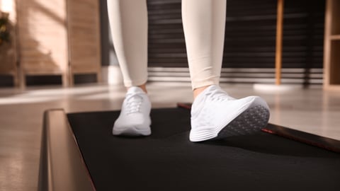 Close up of woman wearing sneakers on a walking pad at home