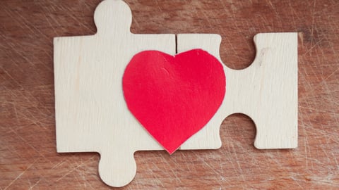 A red heart half on each of two jigsaw puzzle pieces