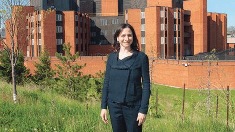 Woman doctor standing in front of a red brick prison compound