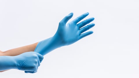 Hands putting on blue medical gloves