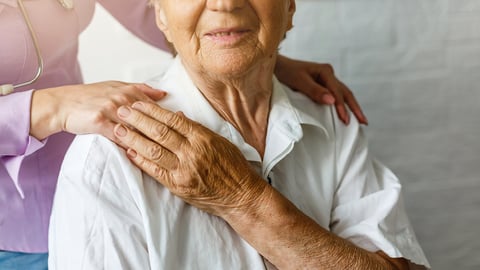 An senior citizen holding a healthcare worker's hand