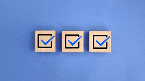 Three blocks of wood with check marks against a blue background