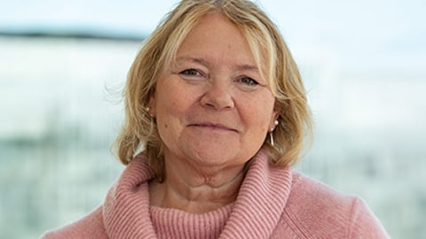 A head shot of a blond woman in a pink top.