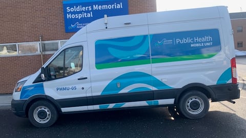 A white and blue van from Nova Scotia health is parked outside a hospital.