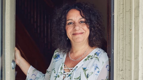 Nanci Frank, consultant pharmacist, smiling in a doorway in a light blue dress