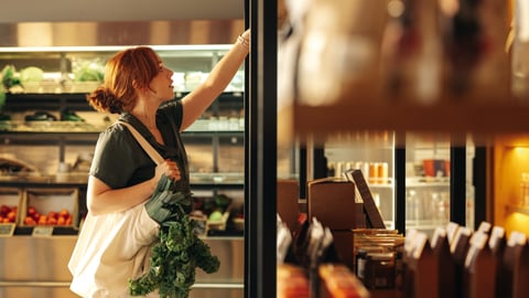 Young woman reaching up to a high shelf in a grocery store