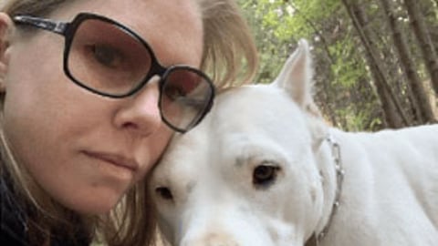 Pharmacy technician Alicia Levnan poses with her white dog