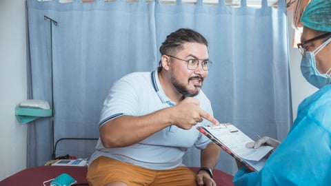 Angry male patient arguing with a doctor in blue scrubs