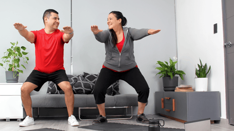 Latino couple doing squats at home gym