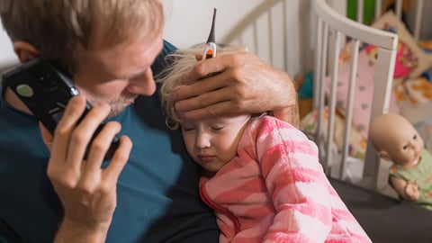 Worried father holding young child while on the phone