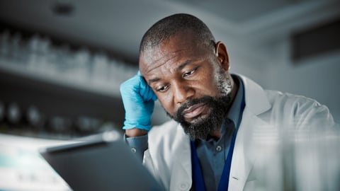 Middle-aged Black scientist looking frustrated at a tablet