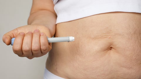 Female belly and hand closeup with Semaglutide Injection pen or insulin cartridge pen. 