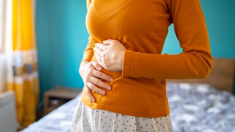 A young woman holding her stomach to indicate discomfort due to IBS