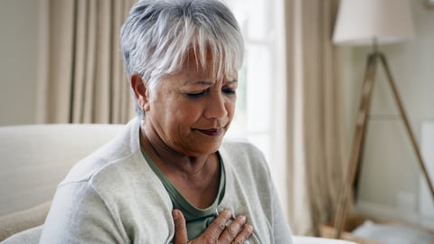 Older woman at home, holding her chest