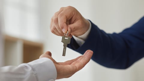 Key exchange. Close up a person handing key to new owner of apartment.