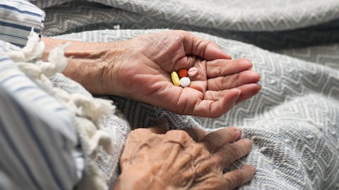 Senior woman's hand holding pills to indicate a potential problem with polypharmacy