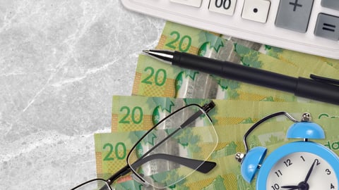 Canadian 20 dollar bills on desk with calculator and glasses