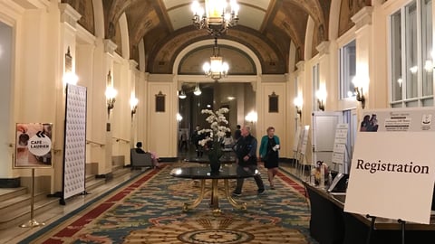 An ornate hallway in the Chateau Laurier in Ottawa with a registration sign on the easel